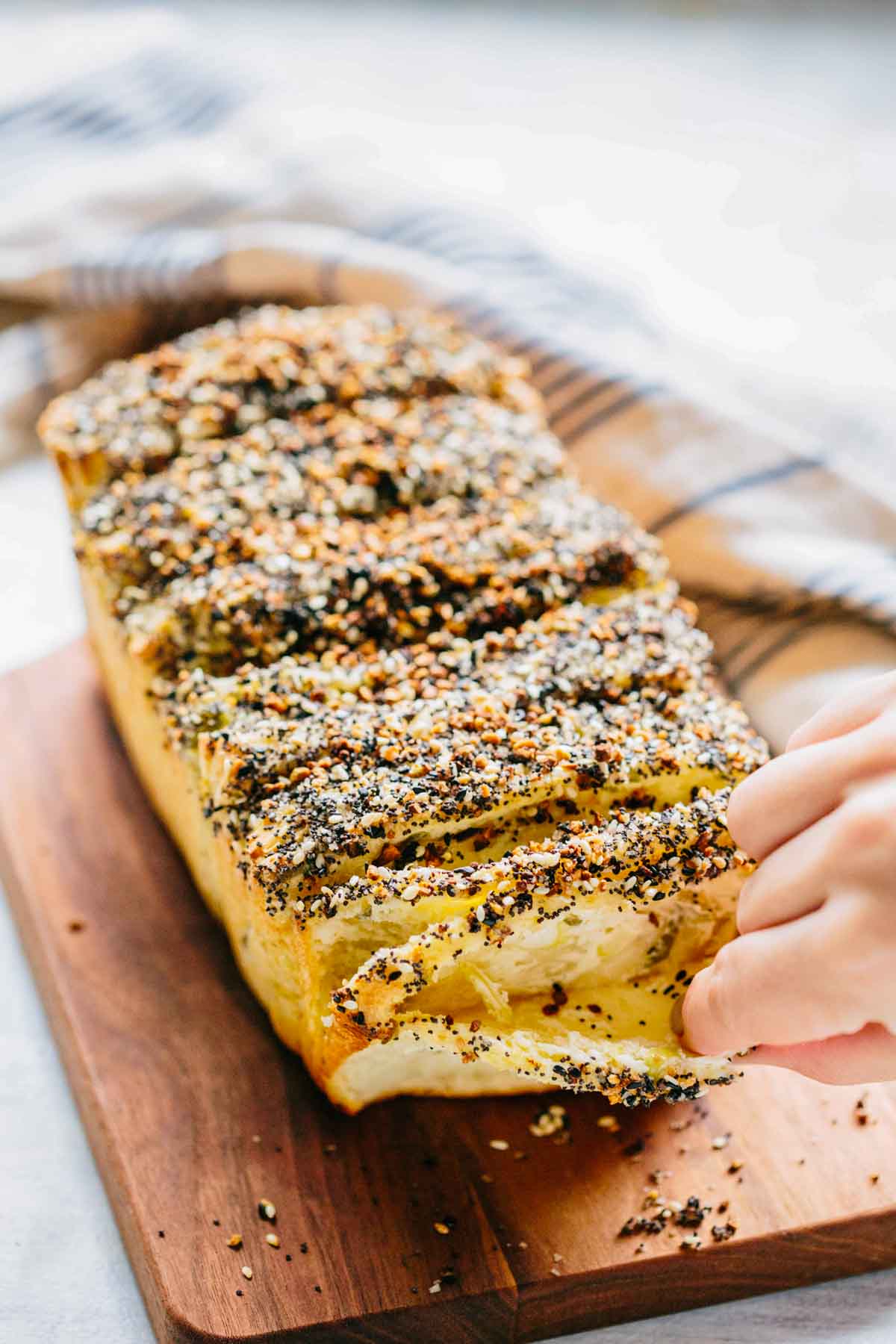 Hand pulling a piece from the loaf, revealing soft, layered interior.