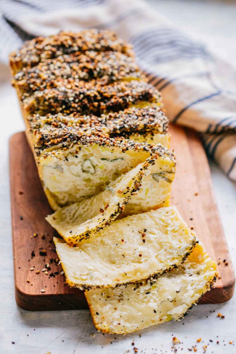 Sliced loaf on a wooden board showing tender, layered interior with scallion cream cheese.