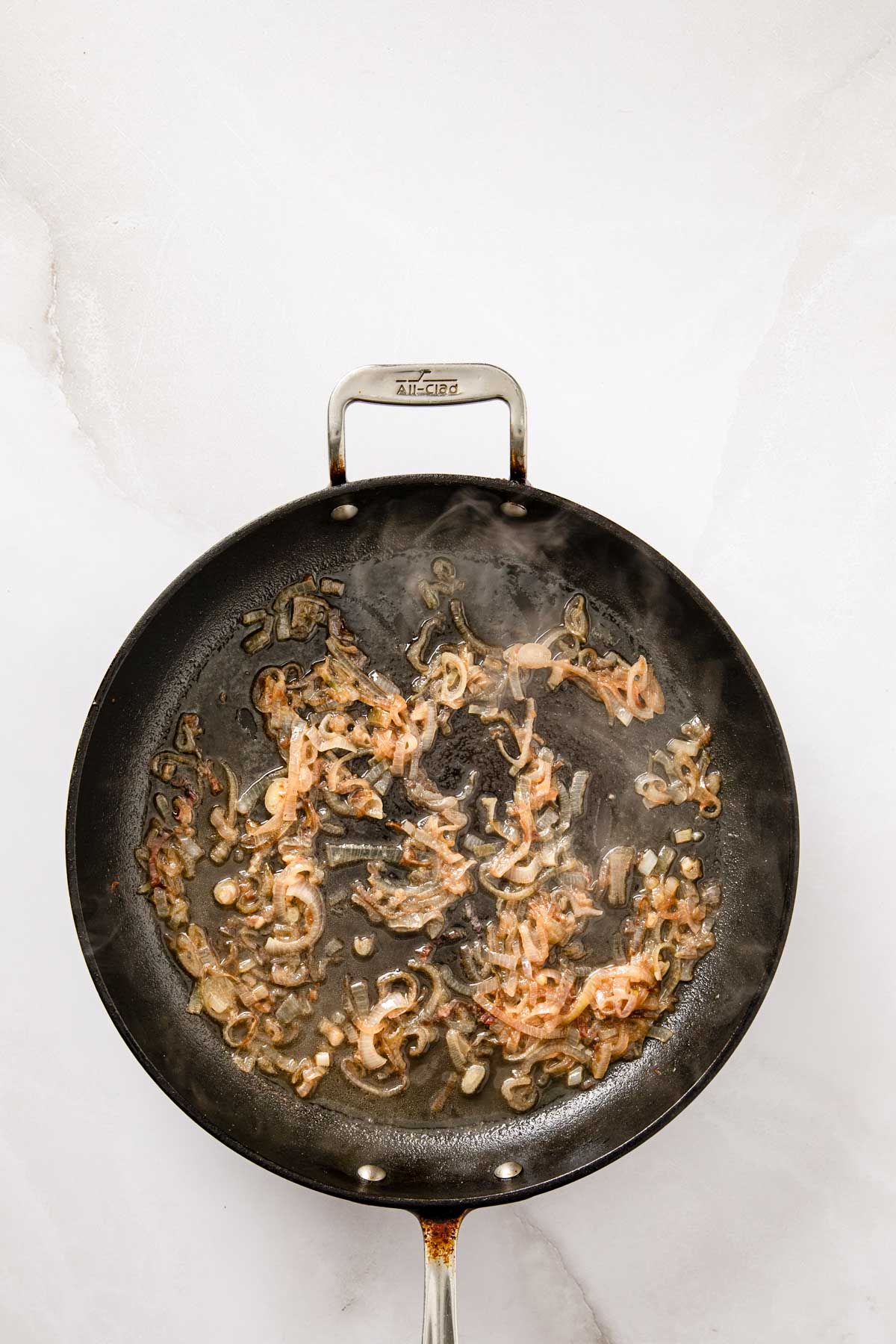 Shallots simmering in chicken stock in the skillet, beginning to reduce.