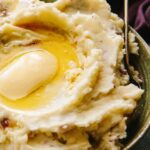 Side view of red skin mashed potatoes showing smooth, creamy texture and glossy butter.
