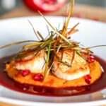 Seared scallops with pomegranate beurre blanc sauce, served over squash purée and topped with crispy leeks.
