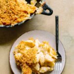 Overhead view of skillet mac and cheese and a serving on a plate with a fork.