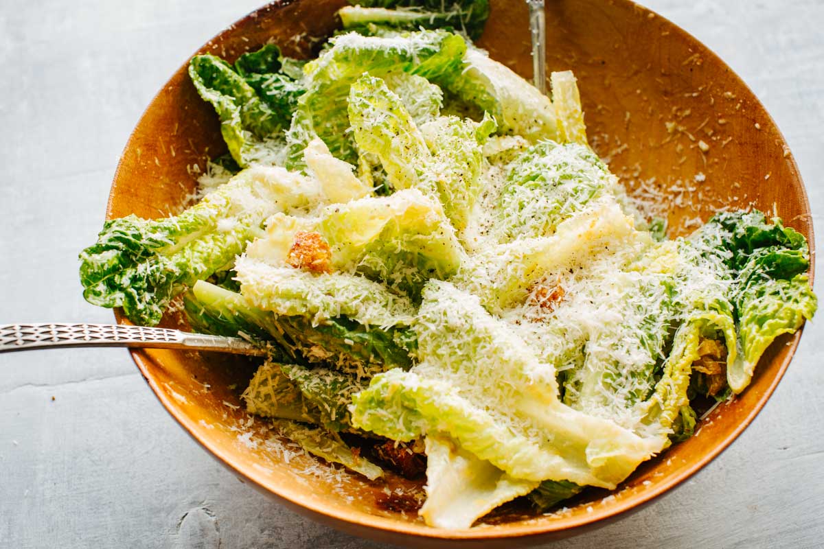 Angled shot of Caesar salad with romaine, visible croutons and a snowfall of freshly grated parmesan.
