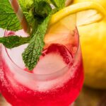 Detailed close-up of a Cranberry Hugo Spritz highlighting condensation, mint garnish, and bright lemon slice.