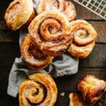 A pile of morning buns on a cloth napkin, showing their rustic spirals, sugar coating, and crisp laminated texture.