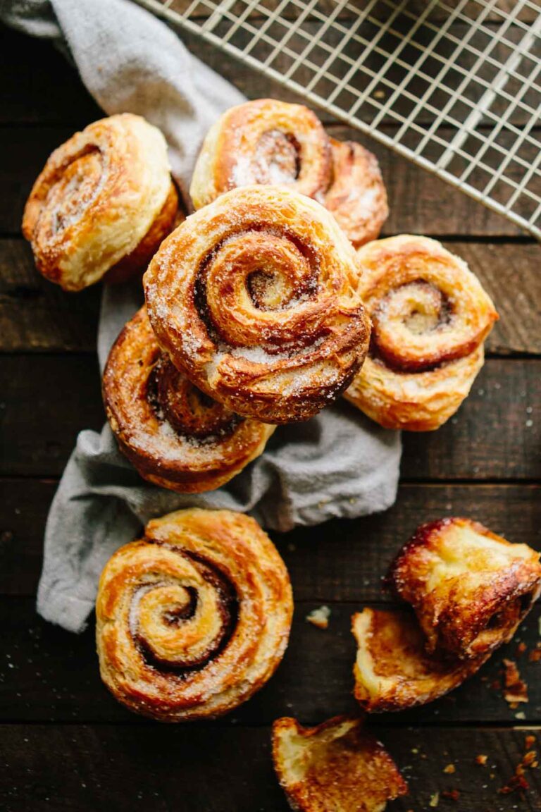 A pile of morning buns on a cloth napkin, showing their rustic spirals, sugar coating, and crisp laminated texture.