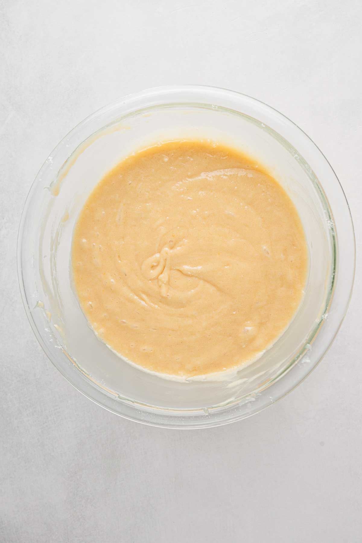 Thick, smooth pizzelle batter resting in a glass bowl after folding in the dry ingredients.