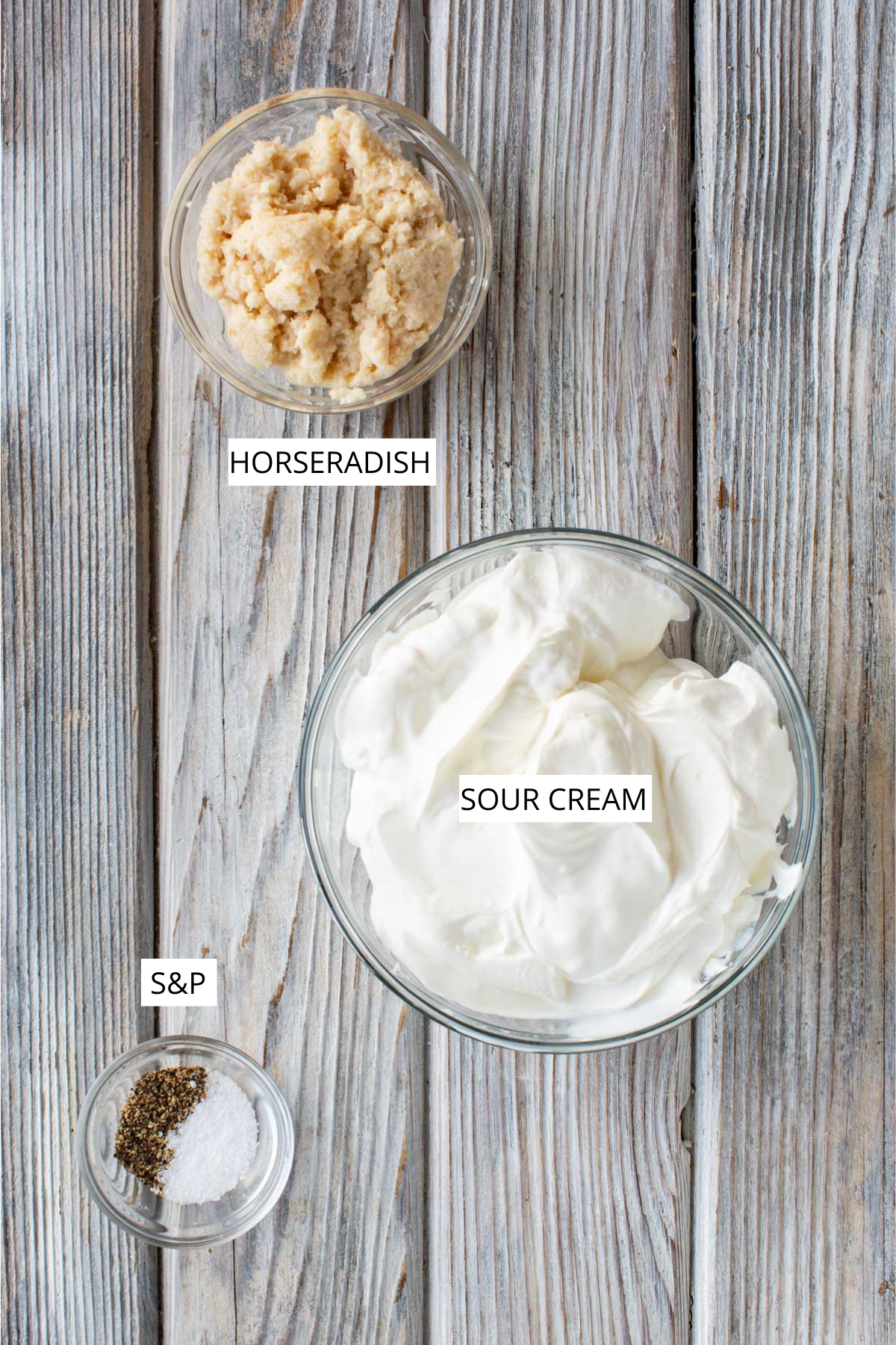 Overhead image showing bowls of sour cream, horseradish and salt and pepper labeled for the recipe.