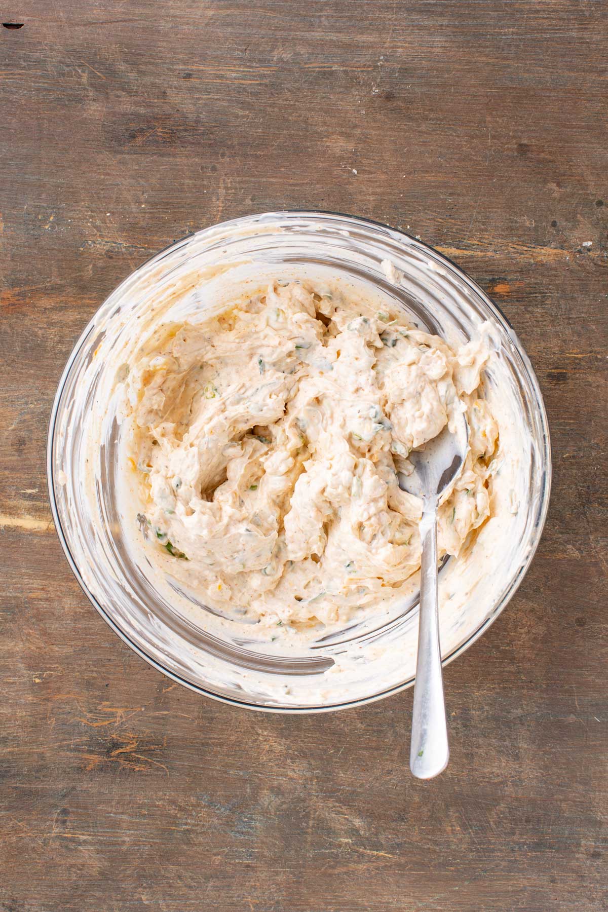 A smooth creamy mixture of cheeses, sour cream and seasonings stirred together in a glass bowl.