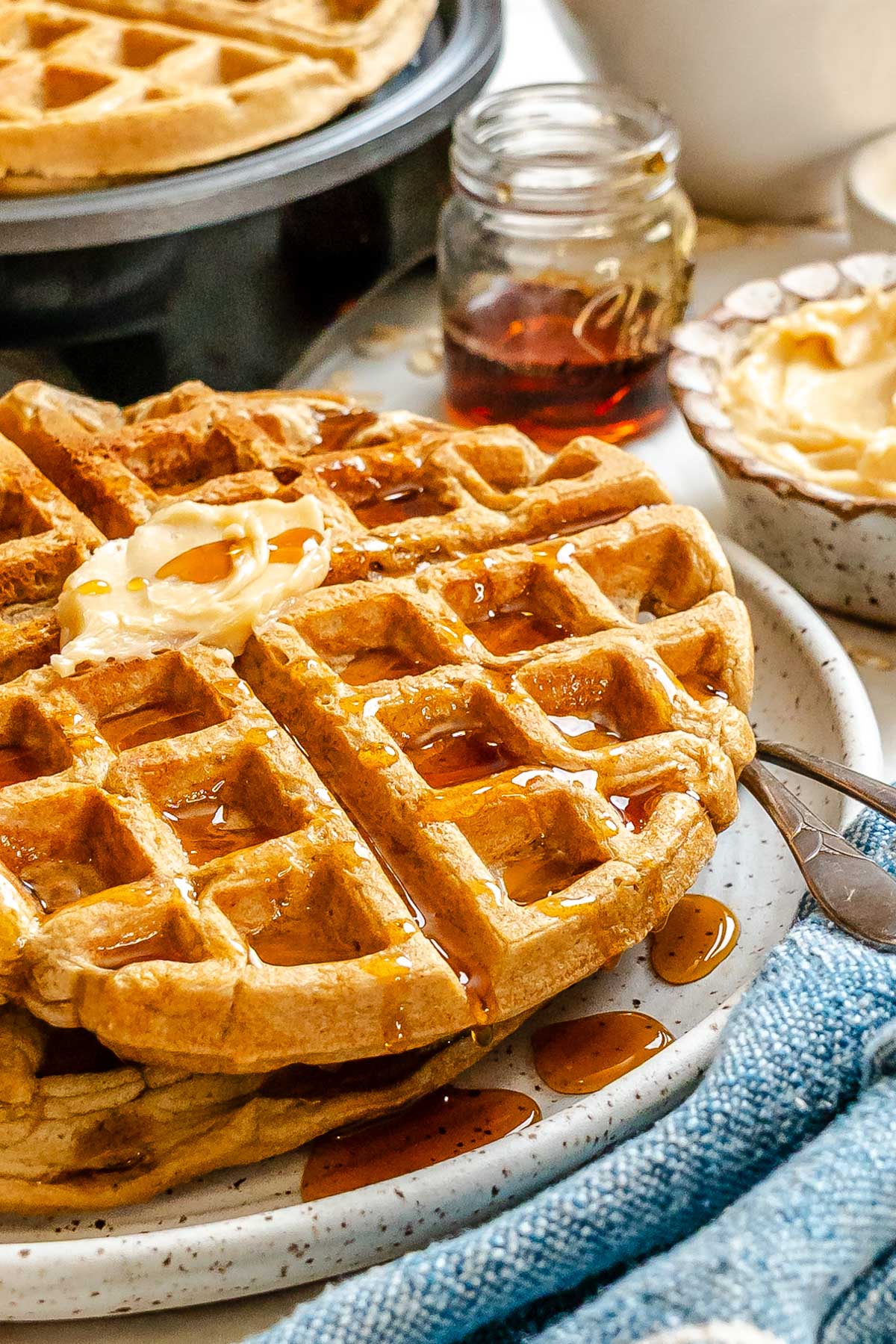 Close-up of oatmeal waffles showing crisp edges and syrup pooling in the waffle pockets.