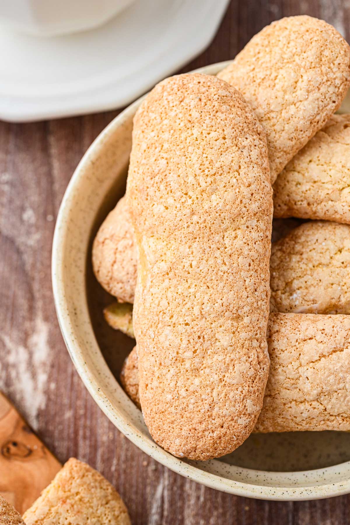 A detailed view of a single ladyfinger cookie showing its crackled exterior and golden color.