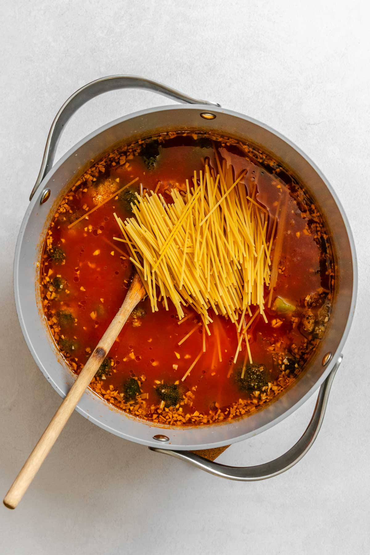 Broken spaghetti added to the simmering broccoli soup before cooking until al dente.