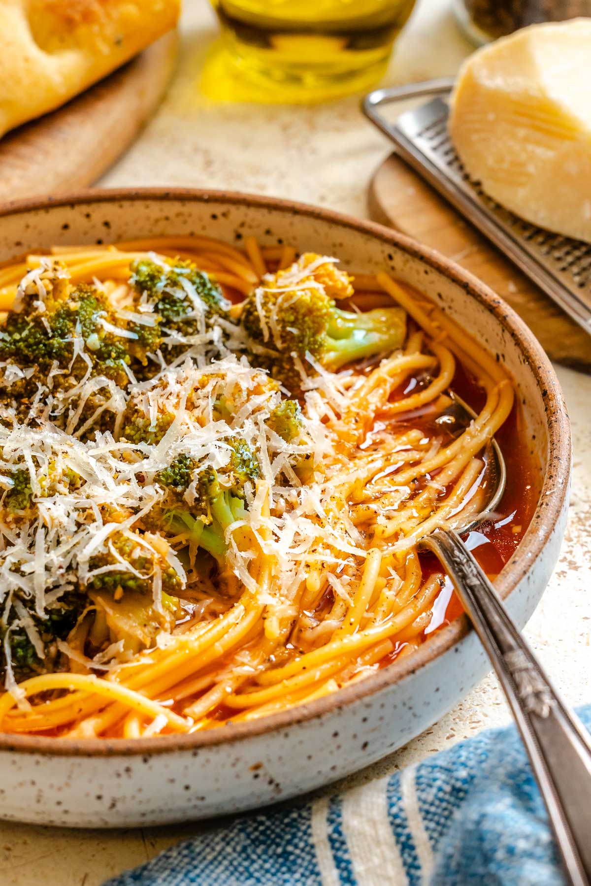 Bowl of Sicilian broccoli soup with spaghetti, tender broccoli florets, and grated cheese on top.
