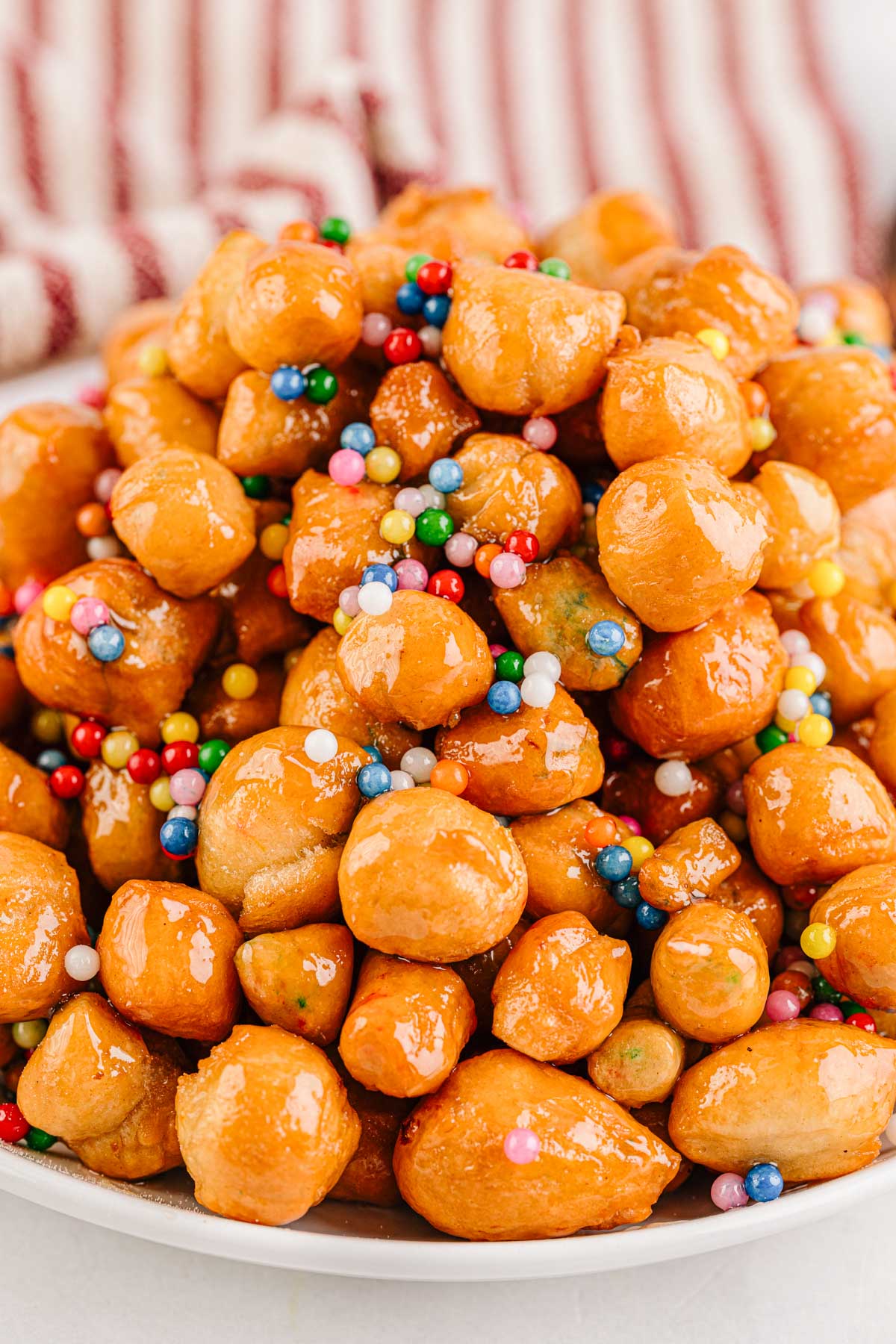 A macro shot highlighting the shiny honey glaze and smooth golden surface of the struffoli with sprinkles throughout.