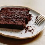 A partially eaten slice of double chocolate banana bread on a plate, with crumbs showing its moist, tender interior.