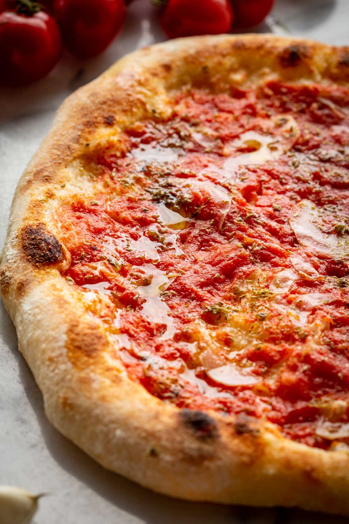 Tight close-up of Neapolitan pizza marinara highlighting the soft dough, blistered edges and chunky tomato sauce.