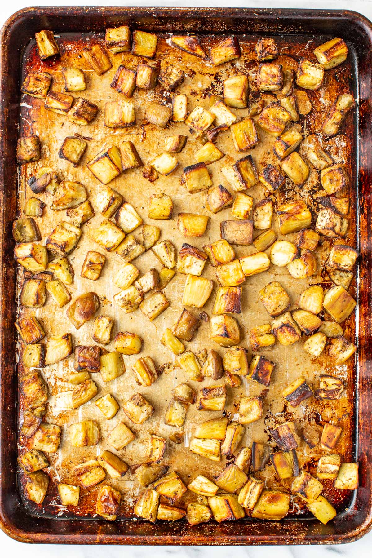 Golden brown roasted eggplant cubes on a baking sheet fresh from the oven.