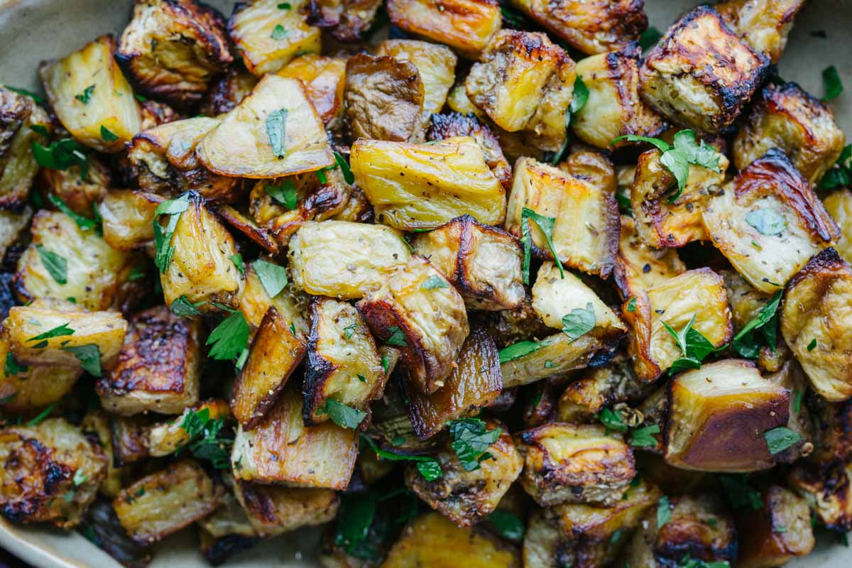Close-up of roasted eggplant cubes topped with fresh chopped parsley.